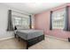 Bedroom with pink accent wall and black platform bed, complemented by natural light from two windows at 4251 Magnolia Ave, Leesburg, FL 34748