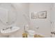 Bright half bathroom with pedestal sink, round mirror, and artwork enhancing the decor at 4328 Acorn Ct, Davenport, FL 33837