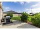 Cozy back patio with a grill, lush lawn, and serene privacy wall, ideal for outdoor relaxation and entertaining at 463 Kayla Ct, The Villages, FL 32163