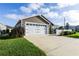 Well-maintained home exterior featuring a two-car garage and lush green lawn at 463 Kayla Ct, The Villages, FL 32163
