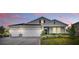 Charming single-story home with a three-car garage and well-manicured lawn at dusk at 485 Halter Dr, Apopka, FL 32712