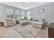 Bright living room features a cozy furniture set, large windows, and wood-look tile flooring at 485 Halter Dr, Apopka, FL 32712