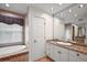 Bright bathroom features a soaking tub with decorative tile and a granite vanity with a large mirror at 4920 Sw 4Th Cir, Ocala, FL 34471