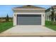 Two car garage with a dark gray door and manicured lawn at 5173 Waypointe Blvd, Apopka, FL 32712
