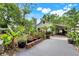 Backyard of home featuring covered parking area, lush landscaping, and brick and concrete driveway at 545 W Cummings St, Lake Alfred, FL 33850