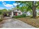 Charming home featuring a red front door, awning, driveway, and mature landscaping at 545 W Cummings St, Lake Alfred, FL 33850