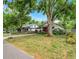 View of the home with a mature tree, landscaping, and a glimpse of the neighbor's house at 545 W Cummings St, Lake Alfred, FL 33850