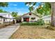 Charming single-story home with a covered porch, bright red door, and lush landscaping at 545 W Cummings St, Lake Alfred, FL 33850