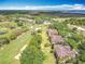 Aerial view of townhomes adjacent to a golf course with mature trees and distant views of a large building at 602 Camino Real Blvd # 602, Howey In The Hills, FL 34737