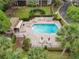 Aerial view of the community pool, featuring lounge seating, palm trees, and well-maintained brick pavers at 602 Camino Real Blvd # 602, Howey In The Hills, FL 34737