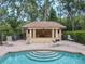 Community pool with tiled roof pool house, outdoor lounge chairs, and well-manicured greenery at 602 Camino Real Blvd # 602, Howey In The Hills, FL 34737