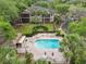 An aerial view features a pool with lounge chairs, a covered seating area, and lush landscaping at 602 Camino Real Blvd # 602, Howey In The Hills, FL 34737