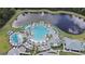 Aerial view of a resort-style pool with lounge chairs, umbrellas, and a lake with a fountain in the background at 6308 Mossy Oak Rd, St Cloud, FL 34771