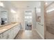 Bright bathroom with dual sinks, granite counters, a large mirror, and a tiled walk-in shower at 6308 Mossy Oak Rd, St Cloud, FL 34771