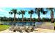 Lakeside outdoor seating area with a built-in grill, palm trees, and serene water views at 6308 Mossy Oak Rd, St Cloud, FL 34771