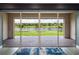 A view of the serene lake and landscaping from the covered brick patio through large sliding glass doors at 6308 Mossy Oak Rd, St Cloud, FL 34771
