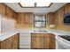 Efficient kitchen with white countertops, double sinks, skylight, and wood-finish cabinets at 74 Stone Haven Ct, Leesburg, FL 34788