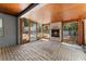 Enclosed patio featuring a brick fireplace, brick flooring, wood-paneled ceiling, and views of the pool at 8198 Se 164Th Pl, Summerfield, FL 34491