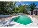 A backyard swimming pool is shown with a white concrete surround, brick coping, and mature landscaping at 8198 Se 164Th Pl, Summerfield, FL 34491