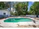 A backyard swimming pool is shown with a white concrete surround, brick coping, and mature landscaping at 8198 Se 164Th Pl, Summerfield, FL 34491