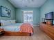 This bedroom has a ceiling fan, laminate floor, dresser with TV, and access to the screened porch at 910 Eagles Lndg, Leesburg, FL 34748