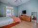 Bedroom with ceiling fan, laminate floor, dresser with TV, and sliding glass doors to the porch at 910 Eagles Lndg, Leesburg, FL 34748