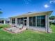 The back of the home shows a lovely enclosed patio and a small patio with chairs, with a neatly kept lawn at 910 Eagles Lndg, Leesburg, FL 34748