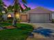 Charming front exterior of a home with a two-car garage, a well-manicured lawn, and lush landscaping under a dusky sky at 910 Eagles Lndg, Leesburg, FL 34748