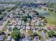 Aerial view of a residential area featuring a single-story home near a tranquil lake, surrounded by mature trees and homes at 1010 Ventura Dr, The Villages, FL 32159