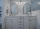 Bright bathroom featuring a double sink vanity, arched mirrors, modern fixtures, and neutral decor at 1010 Ventura Dr, The Villages, FL 32159