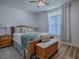 This primary bedroom features wood-look flooring, a ceiling fan, and a large window at 1010 Ventura Dr, The Villages, FL 32159