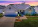 Twilight image of a charming home with manicured lawn, two car garage, and decorative details on the facade at 1010 Ventura Dr, The Villages, FL 32159