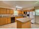 Bright kitchen featuring oak cabinetry, a center island, and modern black appliances, ideal for cooking and entertaining at 10166 Cr 671, Bushnell, FL 33513