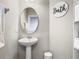 Small bathroom featuring a pedestal sink, neutral colors and a circular mirror at 1051 Nathan Ridge Rd, Clermont, FL 34715