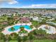 Aerial view of a community pool featuring a splash pad, tropical landscaping, playground, and ample parking at 1051 Nathan Ridge Rd, Clermont, FL 34715