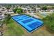 Aerial view of vibrant blue tennis courts surrounded by green space, offering a great recreational amenity at 10689 Se 174Th Loop, Summerfield, FL 34491