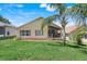 The back of a well-maintained home with a green lawn and a screened porch, bordered by mature trees and neighboring houses at 1159 Greenley Ave, Groveland, FL 34736
