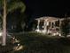Well-maintained lawn with a pergola, lush plantings, and landscape lighting at night at 11860 Se 179Th St, Summerfield, FL 34491