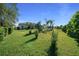 Lush backyard featuring green grass, palm trees, meticulously maintained shrubs, and the home's exterior at 11860 Se 179Th St, Summerfield, FL 34491