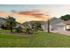 Charming single-story home with manicured lawn, brick driveway, and lush landscaping, complemented by a serene sunset backdrop at 11860 Se 179Th St, Summerfield, FL 34491