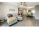 Cozy living room features gray couches, a ceiling fan, wood-look floors, and an adjacent dining and kitchen area at 11995 Callicarpa Ln, Leesburg, FL 34788