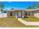 Inviting front entrance with decorative landscaping, a well-manicured lawn, and a freshly painted exterior at 12150 Se 88Th Ct, Belleview, FL 34420
