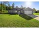 Charming home featuring solar panels, a well-maintained lawn, and an attached garage at 12817 Sw 77Th Cir, Ocala, FL 34473