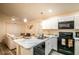 Modern kitchen featuring marble countertops, white cabinetry, and a black appliance package overlooking the living space at 1282 Cottage Cir, Tavares, FL 32778