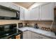 Modern kitchen with stainless steel appliances, marble countertops and white cabinetry, offering ample storage at 1282 Cottage Cir, Tavares, FL 32778