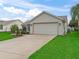 Home's front exterior view with an attached garage, a well-maintained lawn, and a tidy landscape at 1307 Galindo Pl, The Villages, FL 32159