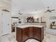 An open kitchen with granite countertops and dark wood cabinets overlooks the living room at 1307 Galindo Pl, The Villages, FL 32159