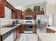 An open kitchen with stainless steel appliances, granite countertops, and dark wood cabinets at 1307 Galindo Pl, The Villages, FL 32159