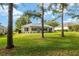 The backyard of the house has a large grass area with trees and landscaping at 13190 Se 93Rd Cir, Summerfield, FL 34491