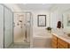 Well-lit bathroom with a glass-enclosed shower, garden tub, and a decorative window at 13190 Se 93Rd Cir, Summerfield, FL 34491